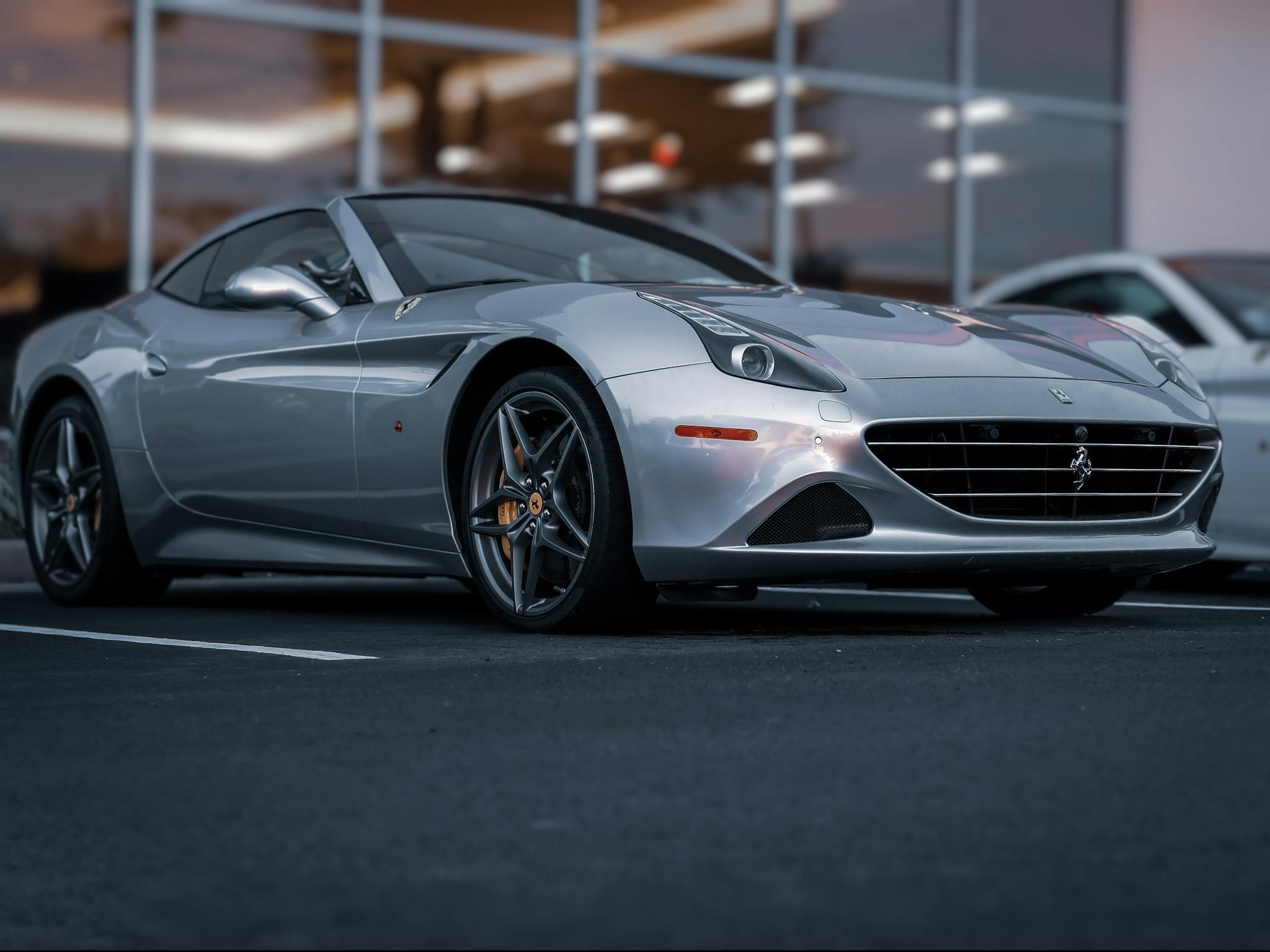 A sleek silver luxury sports car parked in a lot, showcasing elegant design and speed.