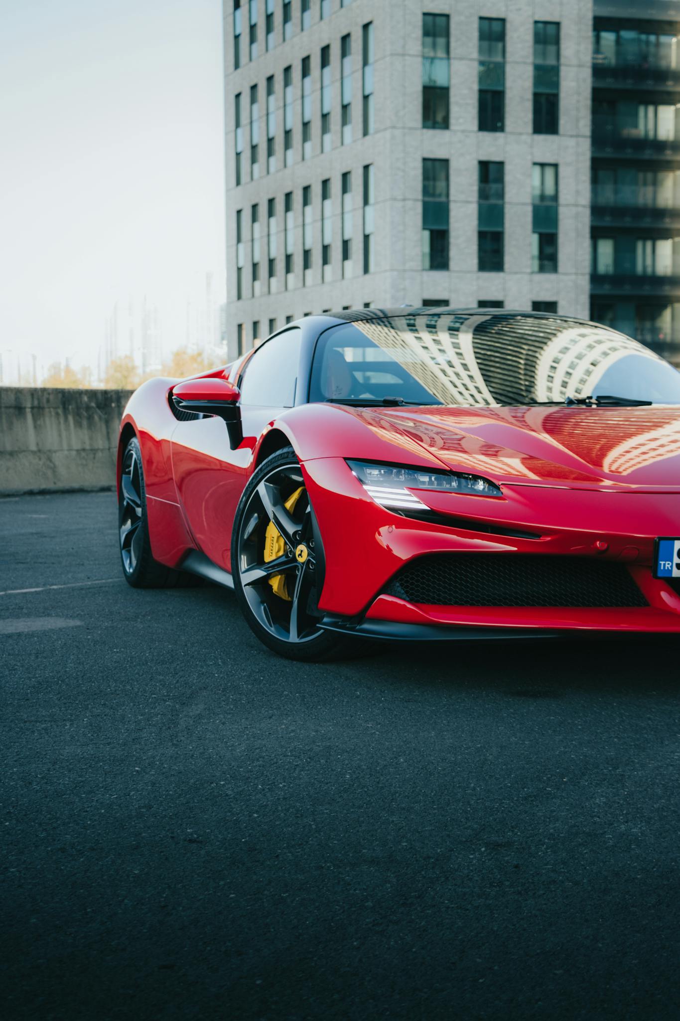Capturing a sleek red sports car parked against an urban backdrop, showcasing luxury and style.